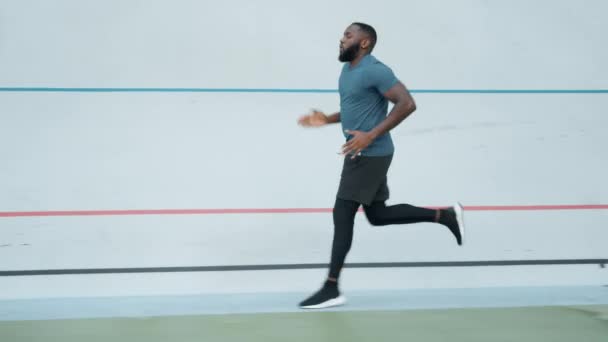 アフリカ系アメリカ人男性がスタジアムでジョギングしている。カーディオワークアウトを屋外で行うランナー — ストック動画