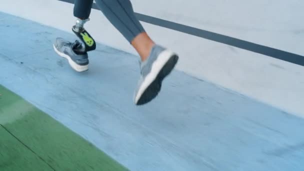 Jogger met kunstmatige ledematen in het stadion. Meisje doet cardio buiten — Stockvideo