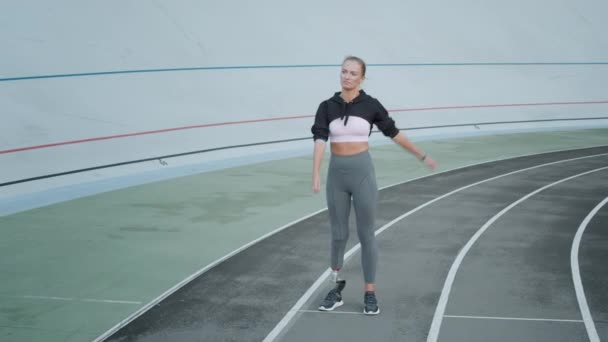 Joggare med artificiell lem uppvärmning på rätt spår. Kvinnan sträcker ut händerna på stadion — Stockvideo