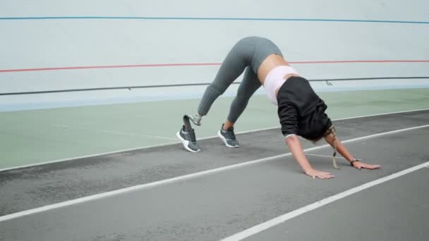 Mujer discapacitada practicando yoga en el estadio. Deportiva haciendo ejercicio en pista — Vídeos de Stock