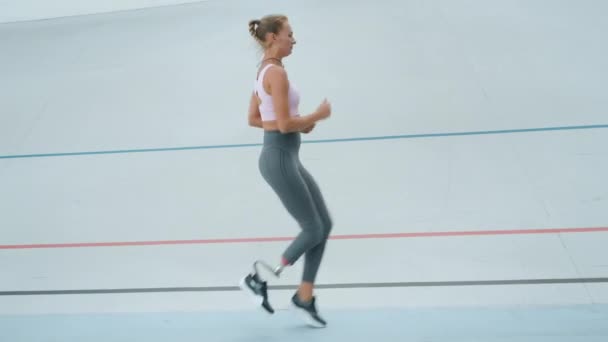 Funktionshindrade kvinna gör höga knä kranar under träningen. Idrottare joggar på kapplöpningsbanan — Stockvideo