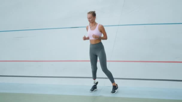 Stadyumda yan yana zıplayan yapay bacaklı bir kadın. Açık havada koşucu eğitimi. — Stok video