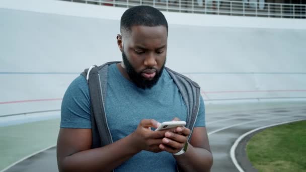 Hombre leyendo malas noticias en el teléfono móvil. Jogger usando smartphone después del entrenamiento — Vídeos de Stock