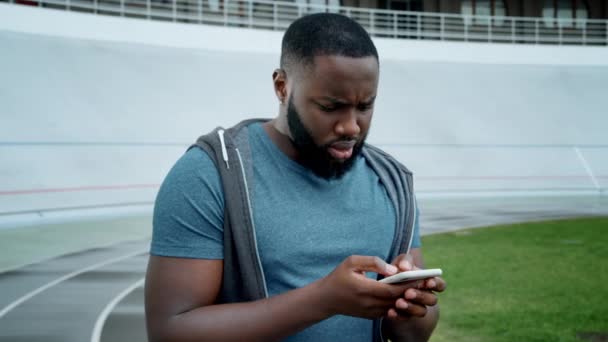 Sportowiec czyta złe wieści na smartfonie. Smutny człowiek korzystający z telefonu komórkowego na zewnątrz — Wideo stockowe