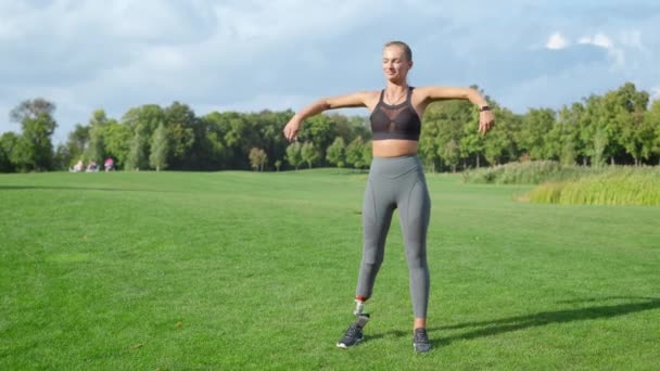 Sportovkyně se zahřívá před tréninkem v parku. Ženské ohřívací paže v zelené oblasti — Stock video