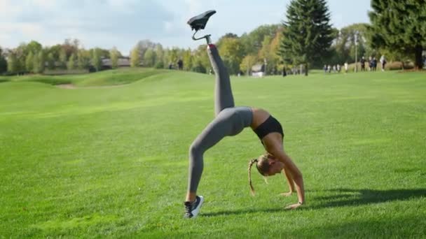 Frau mit Beinprothese beim Yoga auf dem Feld. Mädchen steht in Brückenpose — Stockvideo