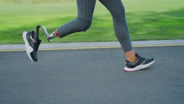 Frau mit Beinprothese läuft auf der Straße. Sportlerinnen trainieren im Freien — Stockvideo