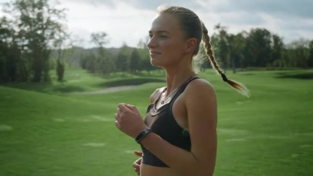Vrolijke sportvrouw joggen in het groene veld. Fit vrouw loopt in het park — Stockvideo