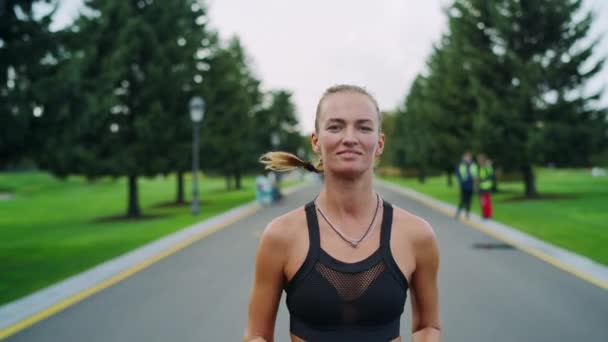 Счастливая спортсменка бегает в парке. Девушка делает кардио тренировки на открытом воздухе — стоковое видео