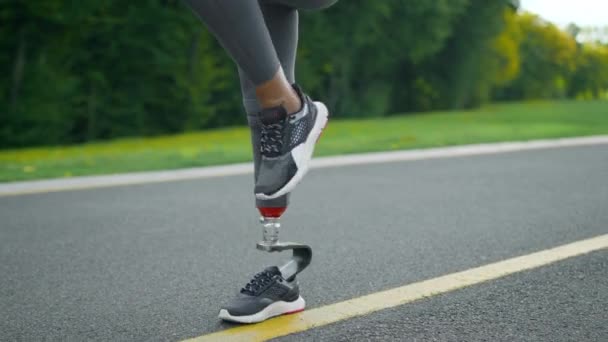 Behinderte Frau, die während des Trainings hohe Kniebeugen macht. Mädchen beine training im park — Stockvideo