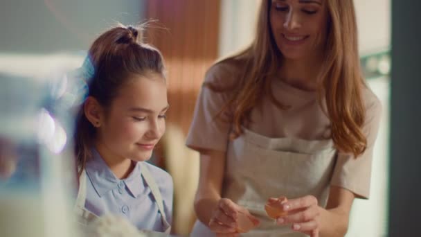 Fröhliche Frau und Mädchen knacken Eier in Rührschüssel auf häuslicher Küche — Stockvideo