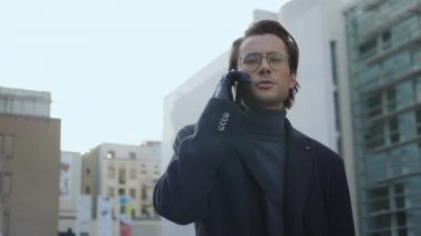 Ciddi bir iş adamı sokakta telefonla konuşuyor. Çalışan toplantı için yürüyor.