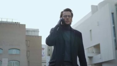 Gülümseyen işadamı caddede telefonla arıyor. Dışarıda yürüyen mutlu yöneticiler.