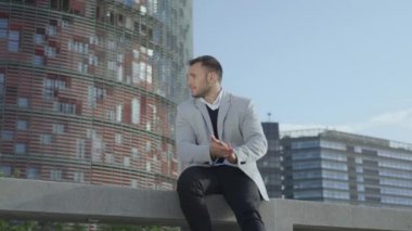 İş adamı caddede bankta oturuyor. Gülümseyen işçi dışarıda mola veriyor.