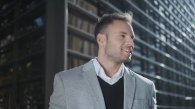 Sokakta kameraya poz veren bir iş adamı. Gülümseyen çalışan dışarıda el ele tutuşuyor.