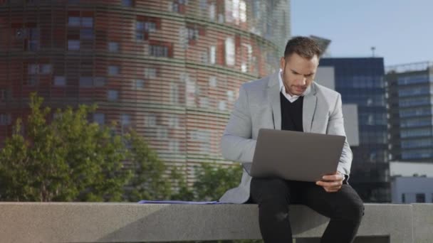 Biznesmen czyta dobre wieści na laptopie na ulicy. Pracownik pracujący na laptopie — Wideo stockowe