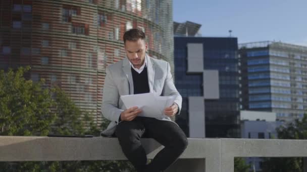 Affärsman tittar på grafer på dokument på gatan. Entreprenör på väg till jobbet — Stockvideo