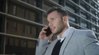 İş adamı sokakta akıllı telefondan konuşuyor. Çalışan dışarıda telefon kullanıyor.