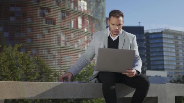Бизнесмен ведет видео-чат на ноутбуке на улице. фрилансер с помощью компьютера — стоковое видео