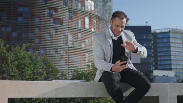 웃고 있는 사업가가 길거리에서 스마트폰으로 비디오 채팅을 하고 있는 모습을 클로즈업 — 비디오