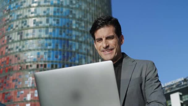 Geschäftsmann liest gute Nachrichten am Laptop auf der Straße. Mann arbeitet am Laptop — Stockvideo