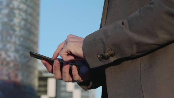 Empresario manos utilizando teléfono inteligente en la calle. Mensaje de escritura del empleado en el teléfono — Vídeo de stock