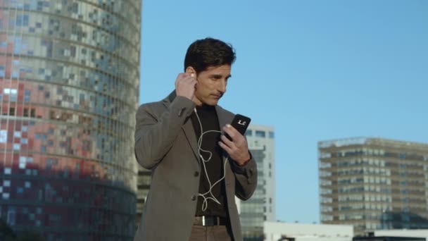 İş adamı sokakta kulaklıkla dolaşıyor. Çalışan dışarıda kulaklık kullanıyor. — Stok video