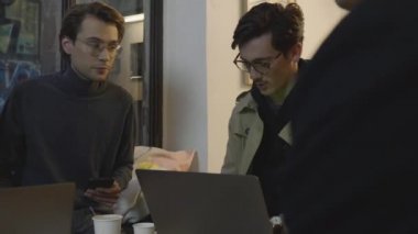 İş adamları kafede toplanıyor. İş adamı akıllı telefondan internete göz atıyor