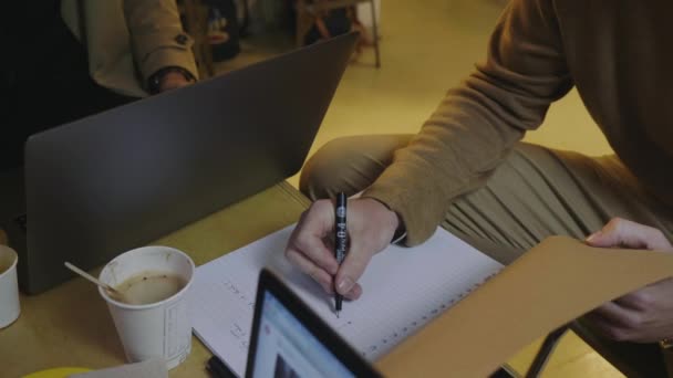 Руки бізнесмена роблять нотатки в блокноті в кафе. Чоловічий фрілансер працює — стокове відео