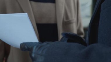 Businessmen looking documents on street. Colleagues standing with papers outside