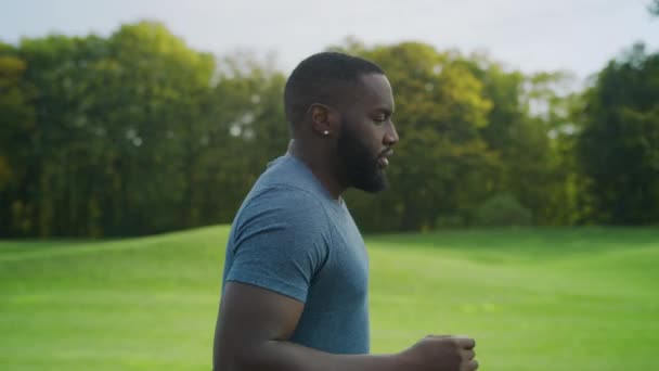 Trött manlig idrottsman som springer i parken. Afro kille utbildning i grönt område — Stockvideo