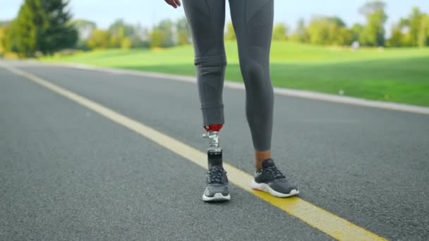 Atleta discapacitado calentando las piernas antes del entrenamiento en el parque. Mujer entrenando al aire libre — Vídeo de stock