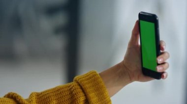 Woman hands holding mobile phone with greenscreen. Girl posing for selfie