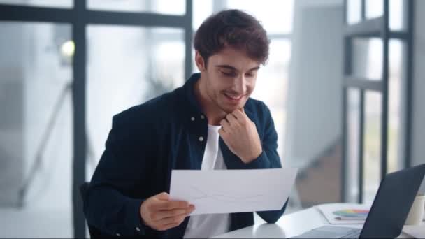 Sonriente hombre de negocios leyendo gráficos de investigación en la oficina en casa — Vídeos de Stock