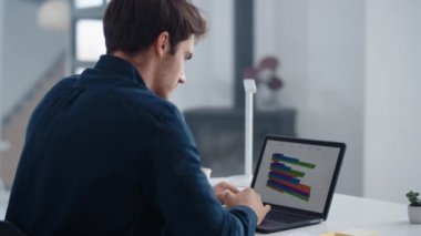 Portrait of male professional looking charts on notebook at home office