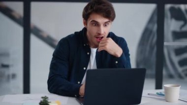 Surprised man getting good news on laptop. Cheerful businessman winning project.