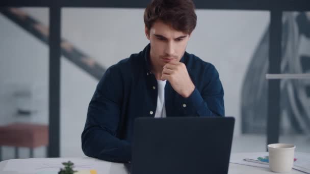 Сфокусированный бизнесмен, работающий на ноутбуке в офисе. Парень читает текст на блокноте — стоковое видео
