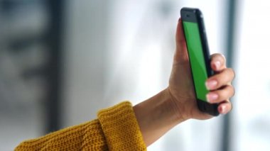Brunette woman holding smartphone with green screen. Girl making video talk