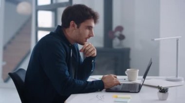 Happy business man working on laptop computer in office. Guy winning project