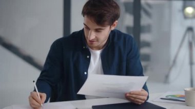 Smiling guy making notes on financial diagram. Man enjoying results of project