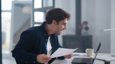 Smiling guy looking results in papers. Successful man making winner gestures