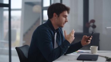 Business man having conference on smartphone. Man waving hands after video call.