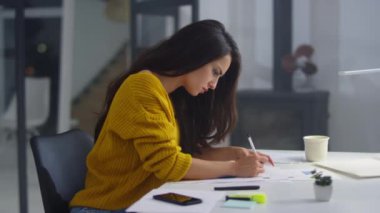 Focused business woman making notes with pencil on bad financial results.
