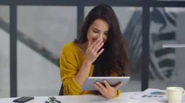 Cheerful business woman laughing with pad. Pretty woman getting funny message