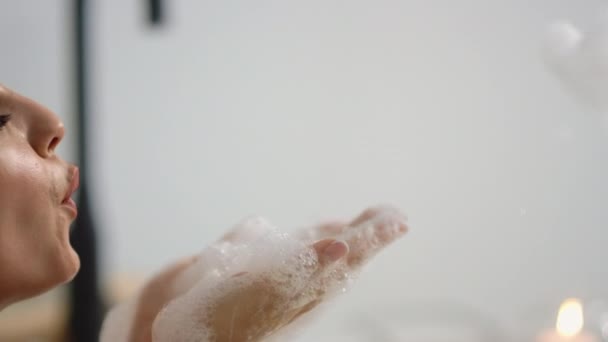 Fechar-se relaxado mulher lavar os braços no banho. Vista lateral da menina bonito soprando espuma — Vídeo de Stock
