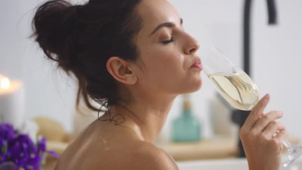 Avslappnad kvinna dricker champagne i badkaret. Sexig tjej kopplar av med ett glas vin. — Stockvideo