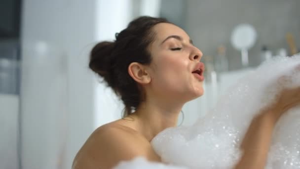 Fechar a mulher quente soprando espuma na banheira. Menina sexy brincando com bolhas — Vídeo de Stock