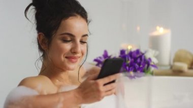 Korkunç kadın küvetteki akıllı telefondan mesaj alıyor. Banyoda mesajlaşan kız.