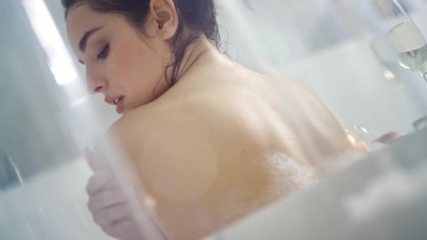 Vista trasera de mujer sensual coqueteando en bañera con velas y champán . — Vídeos de Stock