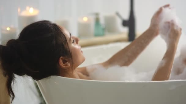 Entspannte Frau, die die Haut mit Schaum berührt. Brünette frau waschen hände im bad — Stockvideo